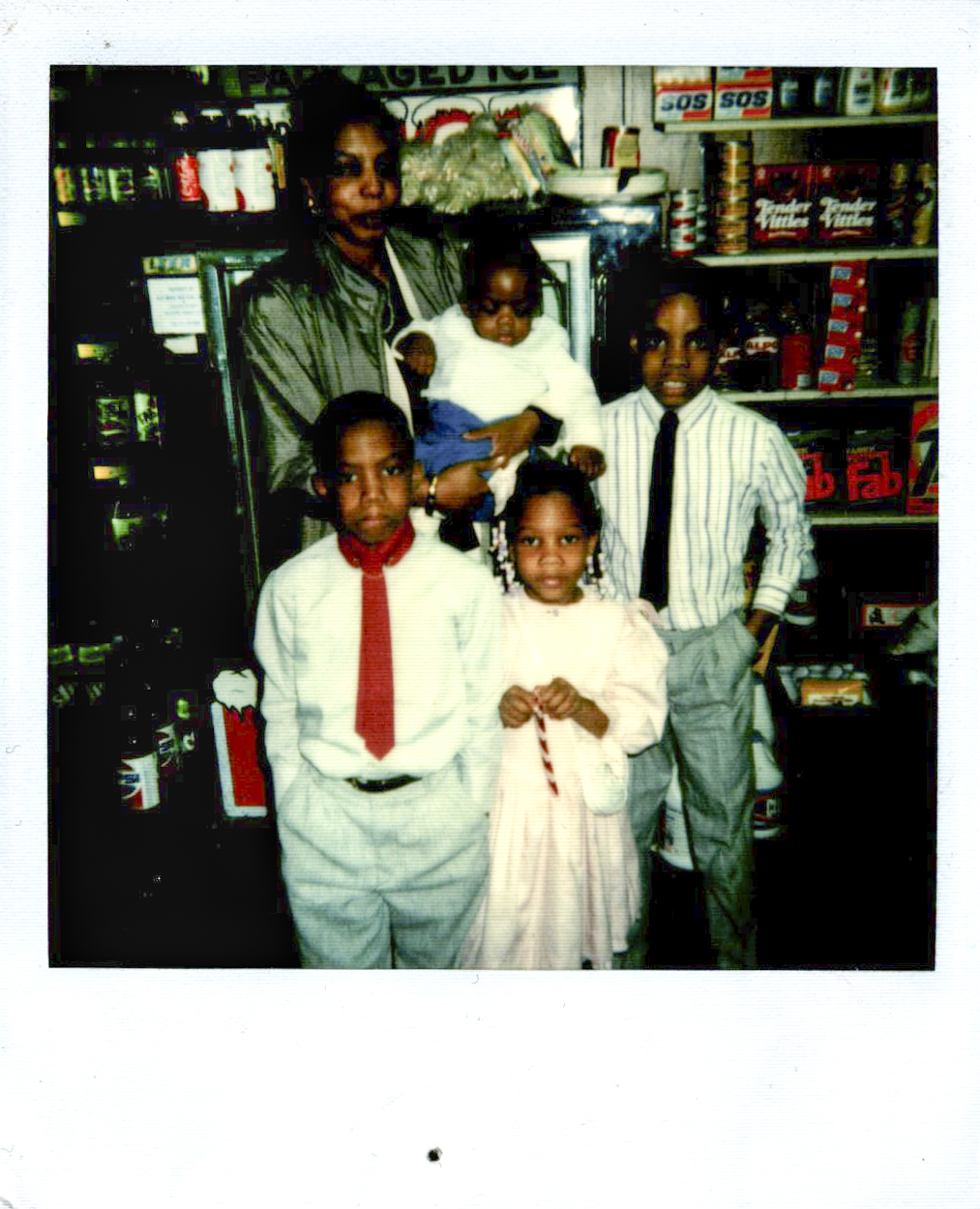 A scan of a polaroid picture of a family. A mother is carrying a toddler
